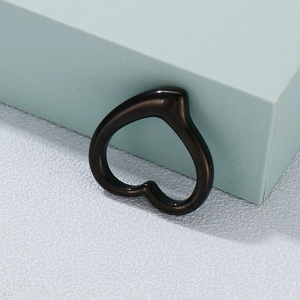 Polished black heart-shaped stainless steel pendant leaning on a blue cube background