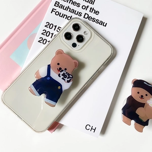 Cute cartoon bear phone grip on transparent case for iPhone Pro series on white desk