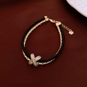 Detail of double-layer leather chain bracelet with gold zircon cross charm and lobster clasp