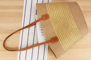 Macro detail of natural straw tote bag featuring golden sequin stripes and leather straps