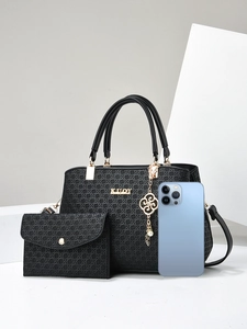 Detail of black woven texture handbag with gold ornaments and smartphone for size reference