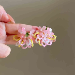 Detailed view of pink beaded flower earrings with tassels and pearl accents in hand