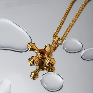 Macro shot of gold cross pendant with tiger eye stone reflecting on mirror with water drops