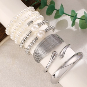 Detail of silver layered bracelet set with pearls and metal bangles on a display stand