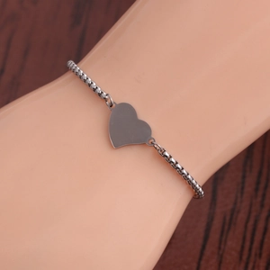 Polished silver stainless steel heart charm bracelet displayed on a model wrist