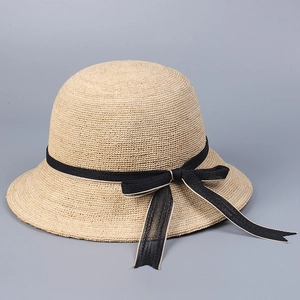 Detailed view of the fine raffia weave and black bow ribbon on this sun hat