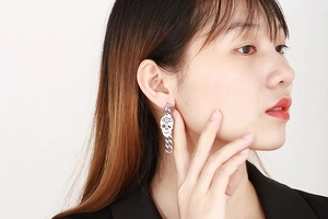 Detailed view of silver skull drop earrings with chunky metal chains on model