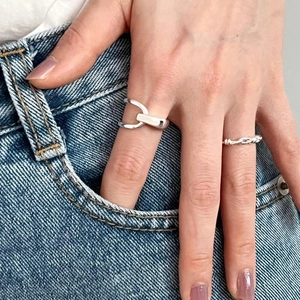 Close-up of silver geometric interlocking and twisted rings worn by hand in denim pocket