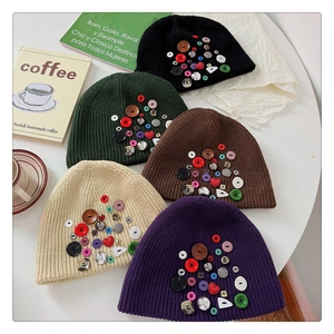 Flat lay of colorful button-decorated knit beanies in black green brown beige and purple