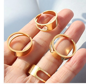 Detail of four 18K gold plated titanium steel rings with hollow rectangular design