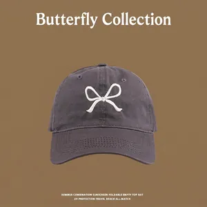 Detail of dark gray baseball cap with white bow embroidery and UV protection fabric