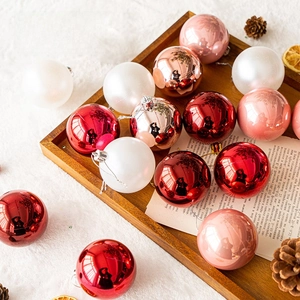 Assorted Christmas tree ball ornaments in red, pink and gold on a cozy tray