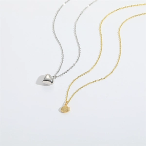 Minimalist silver heart and gold shell pendant necklaces on a clean white background