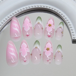 Pink and white stiletto press-on nails with 3D flower art, pearls, and gold bead accents