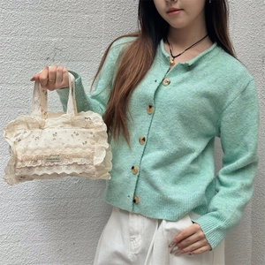 Détail du sac cabas en toile à fleurs avec bordures en dentelle et cardigan en maille