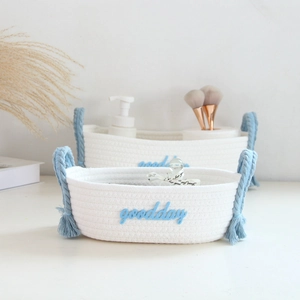 Detail of handcrafted cotton rope storage baskets with blue handles and goodday embroidery