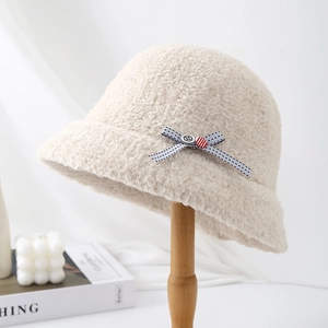 Close-up side view of a warm beige fluffy bucket hat with a delicate bow accent
