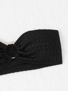 Detail view of black ribbed bikini fabric with mesh cutouts and a gold metal ring