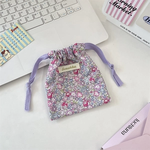 Détail du sac à cordon en tissu floral avec motifs violets et étiquette de marque Sorakka