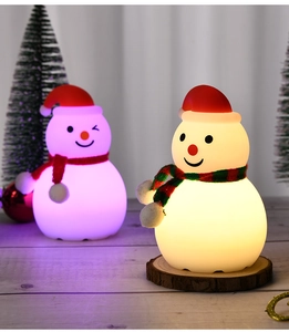 Close-up of silicone snowman night lights glowing in warm yellow and purple pink light