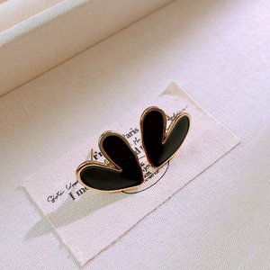 Macro shot of elegant black heart earrings with gold trim on a vintage fabric label