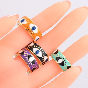 Detail of four colorful bohemian evil eye enamel rings with gold plated edging