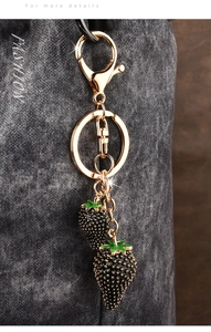 Detailed close-up of double strawberry charms keychain with gold metal hardware and finish