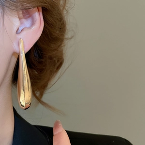Polished gold teardrop earrings shown on model for a modern minimalist fashion look