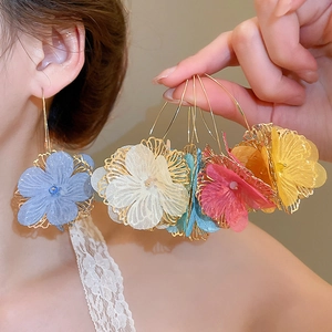 Gros plan de boucles d'oreilles créoles fleurs avec pétales en dentelle et perles