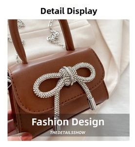 Detail of a brown mini crossbody bag with a large sparkling rhinestone bow and chain