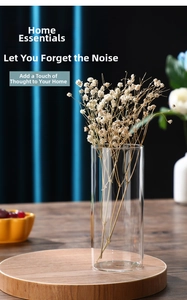 Modern cylindrical glass vase on a wooden base with decorative dried flowers