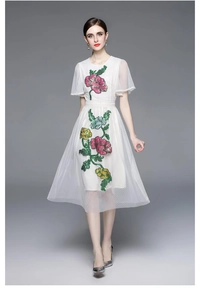 Détail de broderies florales sur tissu en maille blanche d'une robe de style palais