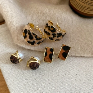 Detail of leopard print earrings set featuring C-shape hoops and faux fur textures