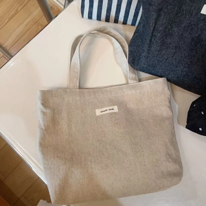 Close-up of minimalist off-white canvas tote bag with a simple wish fabric label