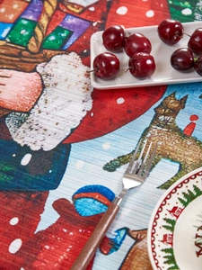 Detailed close-up of festive Christmas tablecloth fabric with Santa and reindeer patterns