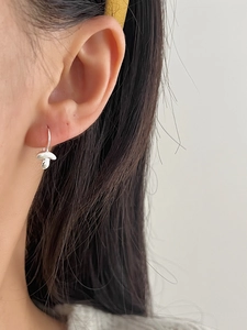 Detail of silver mushroom-shaped hook earring shown on a model for a minimalist look