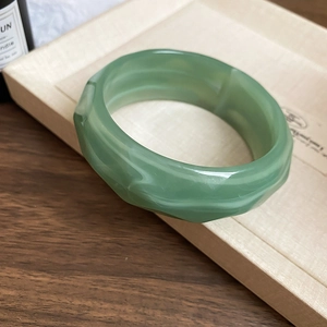 Macro shot of a green resin geometric faceted bangle on a vintage wooden tray