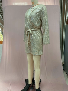 Detail of champagne gold sequined long sleeve romper with deep V-neck and waist tie