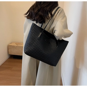 Close-up of black tote bag featuring distinctive woven texture and sturdy shoulder strap