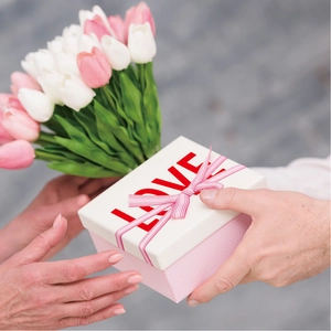 Pink and white textured gift box with ribbon and LOVE print held in hands