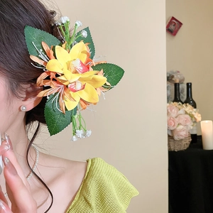 Elegant floral hair clip with yellow and orange petals and green leaves on hair side