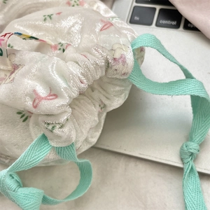 Close-up of floral drawstring storage bag showing soft velvet texture and ribbon detail