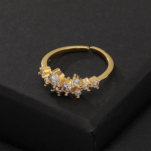Close-up of golden crown ring with sparkling zircon clusters on black textured stand