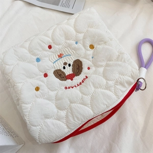 Detail of white quilted heart pattern fabric with cartoon puppy embroidery and red zipper