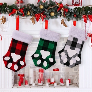 Three buffalo plaid pet paw Christmas stockings hanging on a festive decorated fireplace