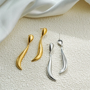 Detail view of 18k gold and silver teardrop earrings on elegant silk fabric background