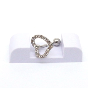 Gros plan d'un piercing de nombril en forme de cœur avec strass sur support blanc