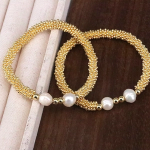 Close-up of handmade gold bead bracelets with white pearls and snowflake accents