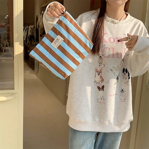 Detailed view of striped canvas makeup bag held by a model for travel storage