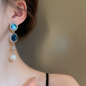 Gros plan de boucles d'oreilles perles avec pierres bleues et cristaux brillants